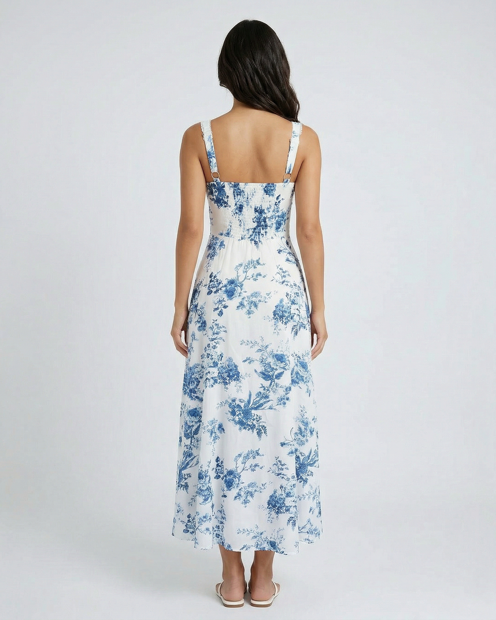 back view of woman wearing a floral dress with blue flowers on a white background