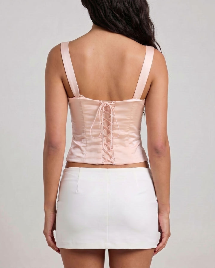 Woman wearing a light pink top and white skirt on a plain background